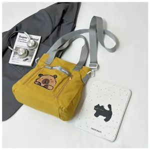 Cute yellow cartoon bear print tote bag for students shown with headphones and jacket