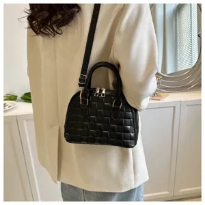 Vista detallada de un pequeño bolso de concha acolchado negro llevado por una modelo.