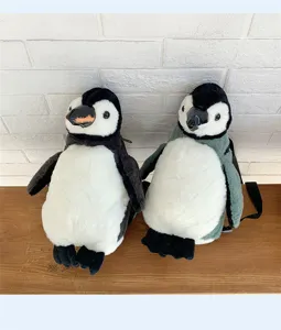 Niedliche Pinguin-Plüschrucksäcke in Schwarz und Grau auf einer Holzoberfläche sitzend.