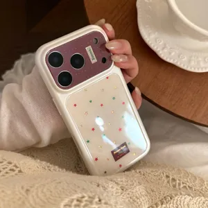 Close-up of cream iPhone case with colorful star patterns and purple glitter accent.