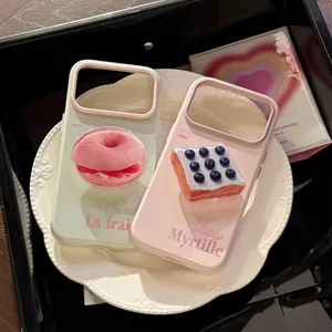 Gros plan de coques de téléphone pastel avec poignées donut 3D et toast aux myrtilles sur assiette.