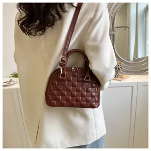 Elegante bolso de mano acolchado marrón oscuro usado con un blazer blanco moderno