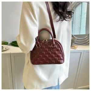Bolso de mano granate texturizado con correa ajustable llevado por una modelo