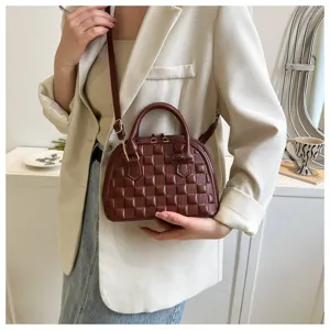 Primer plano de un bolso de concha acolchado marrón combinado con un blazer beige.