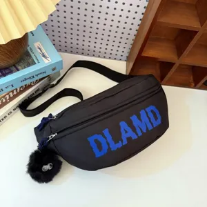 Detailed view of a black nylon chest bag featuring blue DLAMD text and a cute furry charm.
