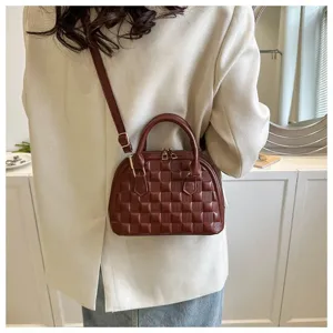 Elegante bolso de mano acolchado marrón con forma de concha usado como bandolera chic