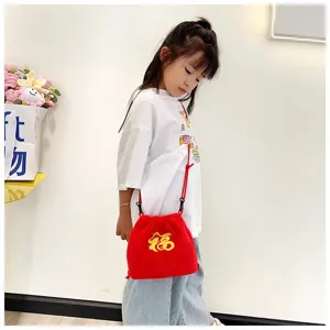 Little girl wearing a cute red plush lucky bag with traditional gold Fu embroidery detail