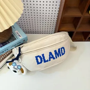 Close-up of a cream nylon chest bag with blue DLAMD print and a cute plush dog charm detail