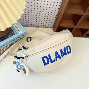 Detailed view of cream nylon chest bag featuring blue DLAMD print and cute white dog charm.
