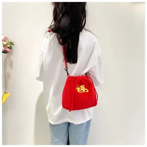 Detailed view of girl wearing a red plush crossbody lucky bag with gold embroidery