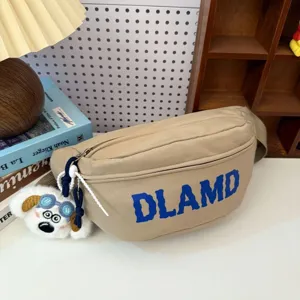 Detailed macro view of a khaki nylon fanny pack featuring blue DLAMD text and a dog charm