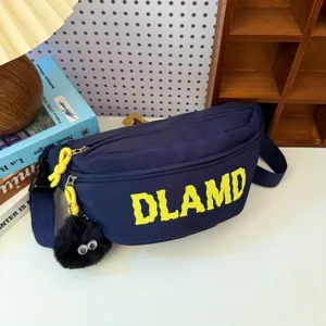 Detailed view of navy nylon chest bag with yellow DLAMD print and fuzzy eye charm