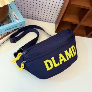 Close-up of navy nylon chest bag featuring yellow DLAMD print and knotted zipper pulls