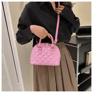 Modelo asiática con un elegante bolso de mano rosa acolchado tipo concha y correa