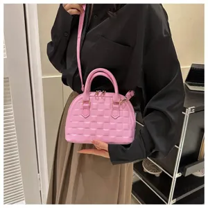 Detalle de un bolso de mano rosa acolchado con correa para el hombro en una modelo.
