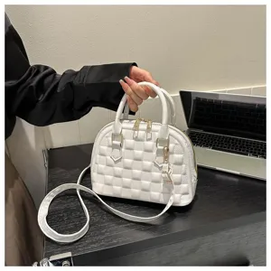 Bolso de mano acolchado blanco moderno con herrajes dorados en un ambiente cotidiano.