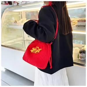 Close-up of cute red plush lucky pouch bag with gold embroidery on a model's side