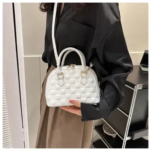 Detalle de cerca de un bolso blanco acolchado con forma de concha y cremallera dorada