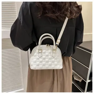 Bolso bandolera de concha blanco con textura a cuadros usado por una modelo en detalle.