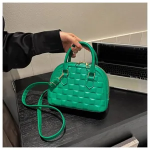 Detalle de un bolso de mano acolchado verde brillante con herrajes dorados y asa superior