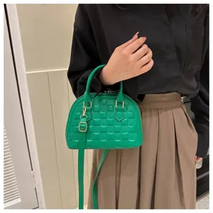 Vista detallada de un bolso concha verde texturizado con correa ajustable para mujer