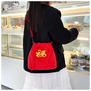 Cute red plush drawstring crossbody bag featuring golden lucky embroidery in a cozy cafe