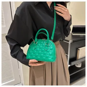 Detalle de un bolso bandolera verde brillante estilo concha con textura de cuadros