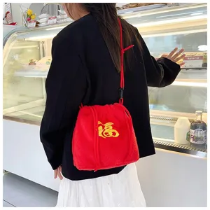 Lifestyle detail of a red plush drawstring crossbody bag with yellow Fu character