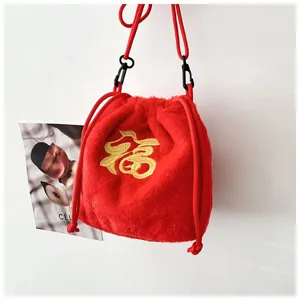 Detail view showing a red plush drawstring bag with traditional golden Fu embroidery.