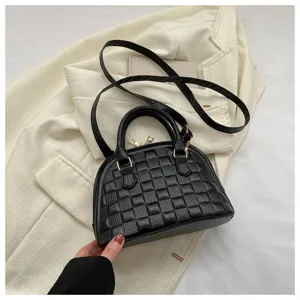 Detalle de bolso negro de concha con diseño de cuadros acolchados y herrajes dorados
