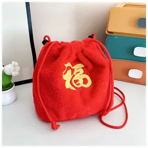 Close-up detail of a festive red plush drawstring bag with embroidered golden 'Fu' character