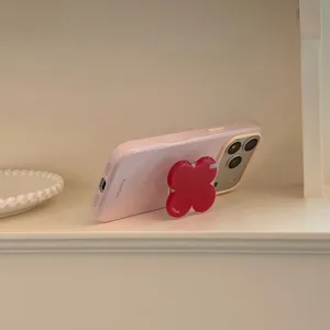 Support de téléphone fleur rouge en acrylique sur une coque iPhone rose sur étagère