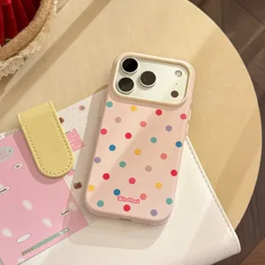 Primo piano di una custodia per iPhone rosa con pois colorati su una scrivania.