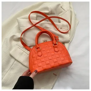 Detalle de un bolso de mano naranja acolchado con forma de concha muy elegante