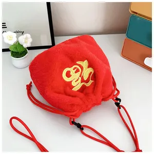 Close-up detail view of a soft red plush drawstring bag with gold Fu embroidery