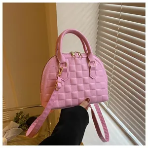 Primer plano de un bolso rosa en forma de concha con patrón de cuadros texturizados.