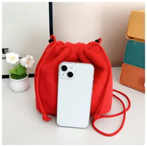 Detail shot of a cute red plush drawstring shoulder bag with a phone for size scale
