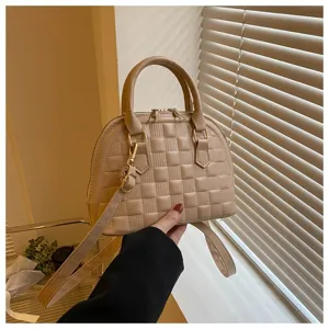 Vista detallada del bolso de mano beige con textura de cuadros y herrajes dorados