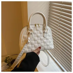 Primer plano de un bolso tipo concha acolchado blanco con elegantes detalles en oro.