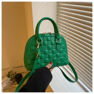 Detalle de un bolso de mano de concha acolchado verde con elegantes herrajes metálicos dorados