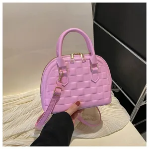 Detalle de la textura acolchada de un bolso de mano rosa con cremalleras doradas.