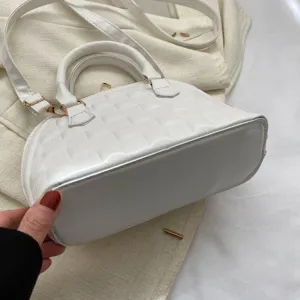 Primer plano del bolso concha blanco que muestra textura acolchada y base sólida