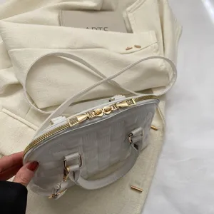 Primer plano del bolso de concha acolchado blanco con cremallera dorada y correa.