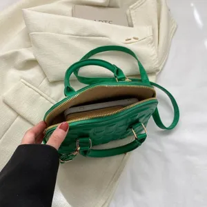 Detalle interior de un bolso acolchado verde que muestra capacidad para móvil y cartera
