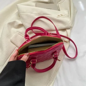 Detalles del interior del bolso de concha rosa con smartphone y cartera dentro.