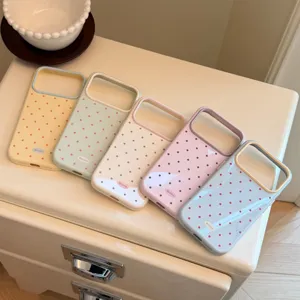 Détail de cinq coques de téléphone à pois pastel disposées sur un meuble de couleur crème