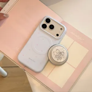 Detail van witte iPhone-hoes met roze sterren en een glinsterende strik telefoonstandaard