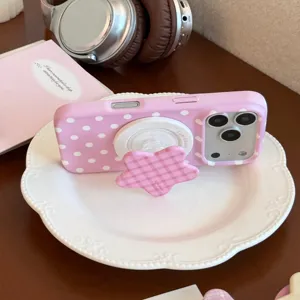 Détail de la coque iPhone à pois roses avec support magnétique en vichy étoilé sur une assiette