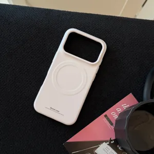 Détail d'une coque de téléphone MagSafe mate crème sur un fond de tissu noir premium