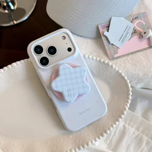 Gros plan d'une coque iPhone blanche avec support étoile à carreaux bleus sur une assiette